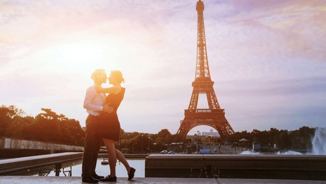 Couple kissing in front of the Eiffel Tower at sunset